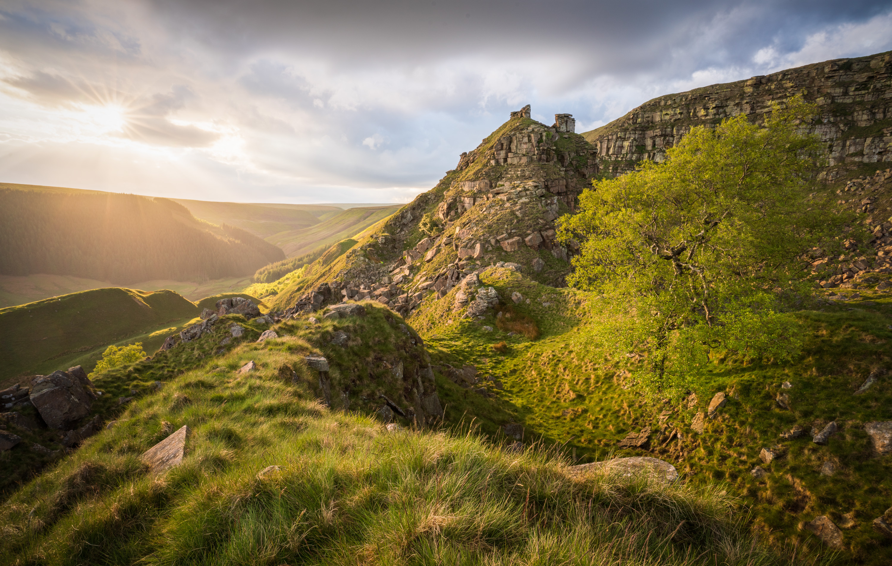 Late afternoon light catching on The Tower of Alport Castles in the Peak District National Park, and on the slopes of Alport Valley in the background. Photograph by Kieran Metcalfe, prints available.